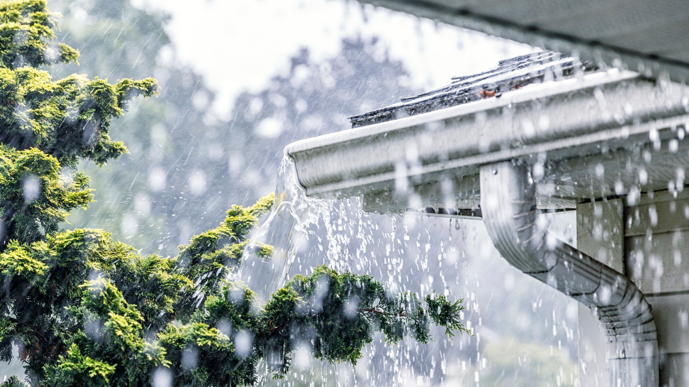 Is Your Greenville Home Ready for Spring Showers (And What’s Hiding in Your Crawl Space) Spring rain flowing from a Greenville home gutter