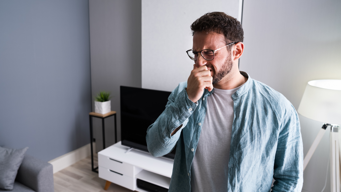 Man covering his nose due to bad smell in apartment, highlighting serious odor problems